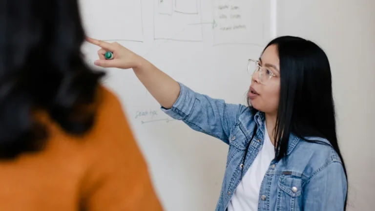 Woman presenting ideas on whiteboard during meeting.