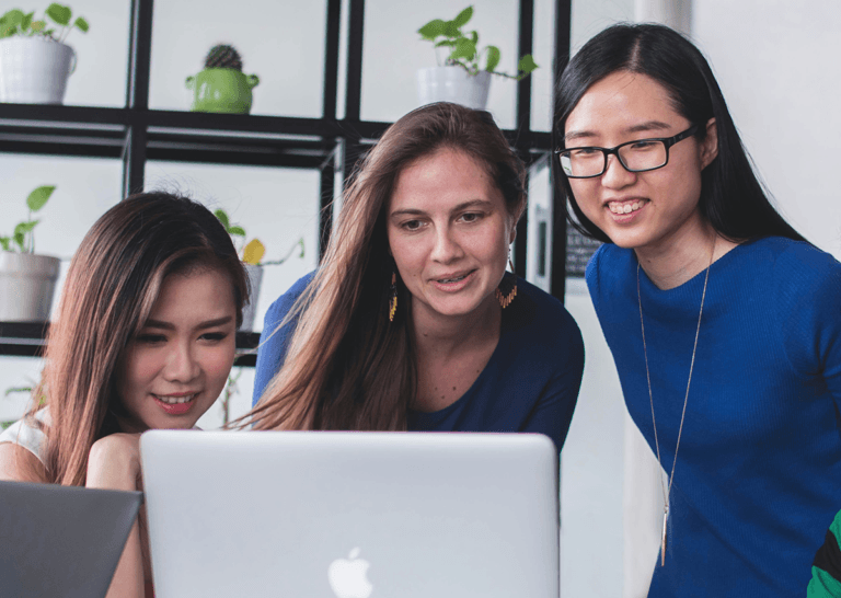 Three women collaborating on a laptop.