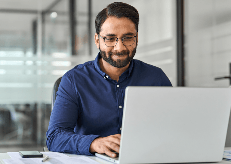 Man smiling at laptop in office