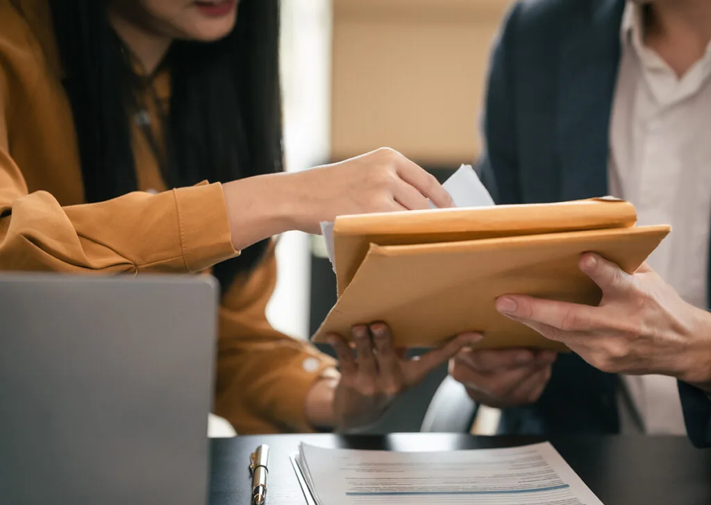 Two people exchanging documents at a desk