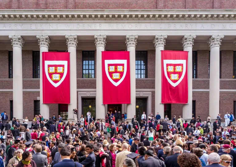 Graduation crowd at library with red banners displayed.