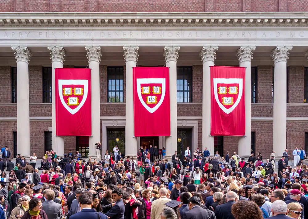 Graduation crowd at library with red banners displayed.